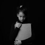monochrome photo of sad child hugging a drawing pad